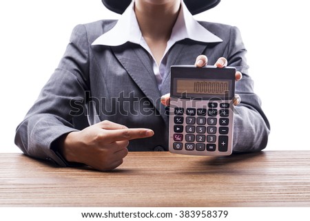 Businesswoman pointing at a calculator on desk.