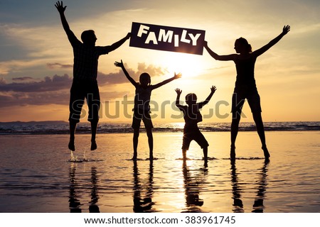 Happy family jumping on the beach at the sunset time. Parents hold in the hands  inscription "Family". Concept of happy family.