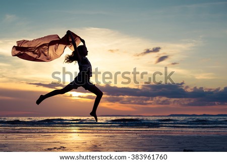 Happy teen girl jumping on the beach at the sunset time