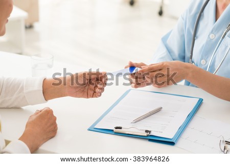 Hands of doctor giving health insurance card to senior patient Royalty-Free Stock Photo #383964826