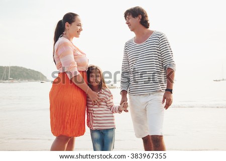 Family walking on the evening beach during sunset, travel photo series.