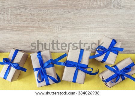 Gift boxes with blue ribbons on a yellow canvas and empty wooden background.Place for text.