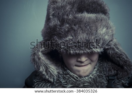 Funny child with fur hat and winter coat, cold concept and storm