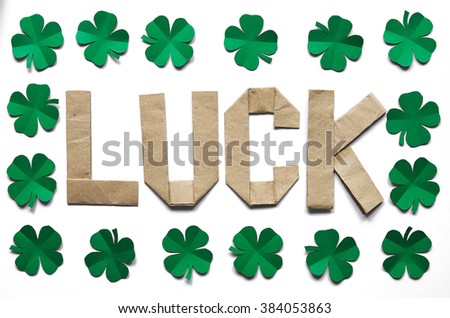 Craft paper origami LUCK lettering on white background isolated. Green clover leaf. St. Patrick's Day greeting postcard template.