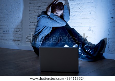 sad and scared female teenager with computer laptop suffering cyberbullying and harassment being online abused by stalker or gossip feeling desperate and humiliated in cyber bullying concept Royalty-Free Stock Photo #384115324