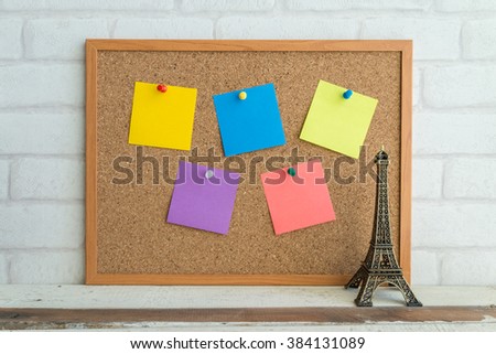 Cork board with colorful blank paper notes and Eiffel tower model