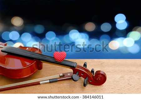 red heart on neck of violin with blur bokeh light in city in blue tone background
