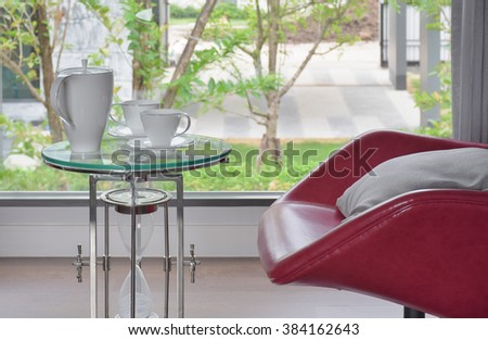 Tea set on glass top table with red easy chair in living room