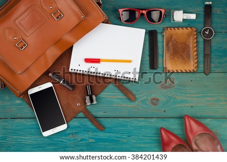 Travel concept - women set with bag, phone, notepad, purse, watch, glasses on blue wooden background. Top view Royalty-Free Stock Photo #384201439