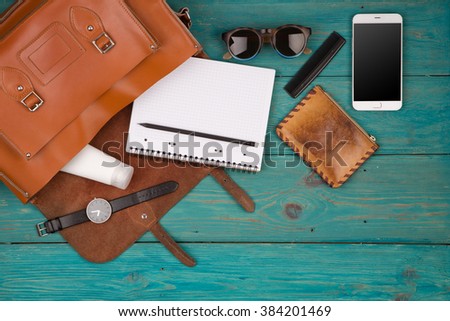 Travel concept - women set with bag with phone, notepad, purse, watch, glasses on blue wooden background. Top view Royalty-Free Stock Photo #384201469