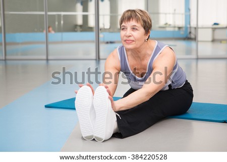 Senior Woman Doing Stretching Exercises In Gym
