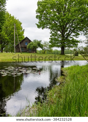 country house with pond and oak trees in green summertime
