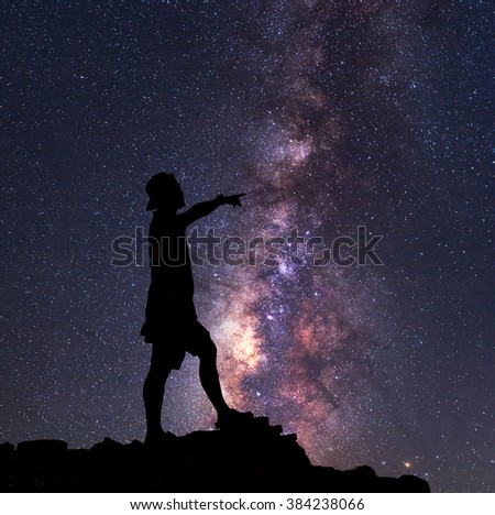 Star-catcher. A person is standing next to the Milky Way galaxy pointing on a star