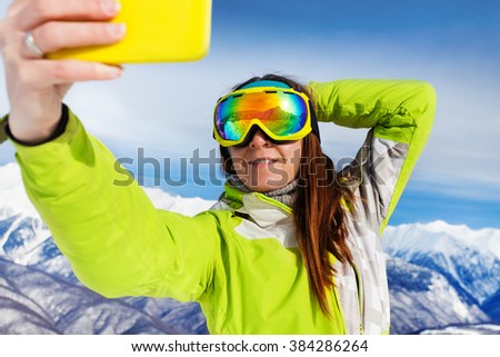 Skier woman take selfie with phone over mountains