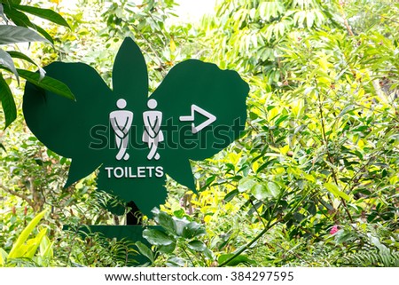 Toilet direction board in the garden,Toilet sign on butterfly shape board style background