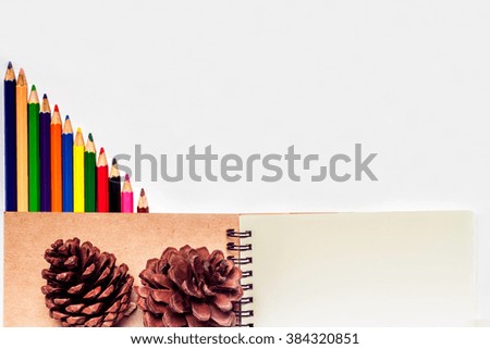 Color pencils with notebook and empty spaces on white background