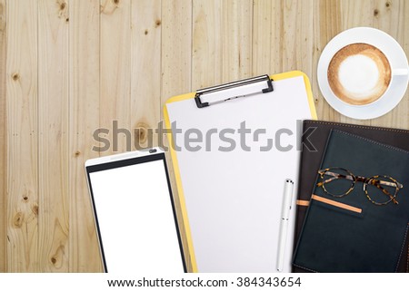 Top view of stuff office desktop and copy space. Analyze data chart show on paper and tablet, planner notebook, glasses and coffee.
