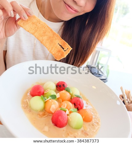 Girl eating delicious colorful fruit ceasar sald with crispy bread and almond slice topping , great fusion food