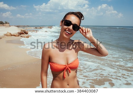 Beautiful young girl flying with seagulls on the sea, the girl in sunglasses and a swimsuit. He smiles and enjoys sea and sun