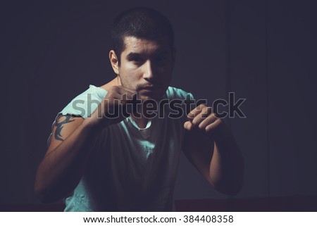 Portrait of a male boxer. Young sporty man on a dark background. Toned image. Fight