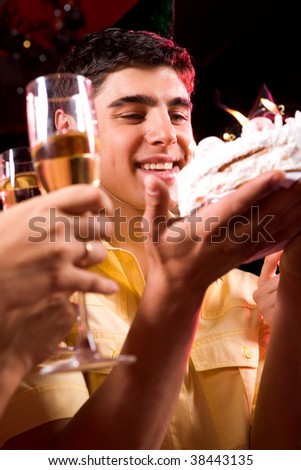 Image of man looking at cake with glasses in human hands near by