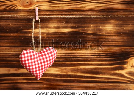 Love heart hanging on rope on a brown wooden background