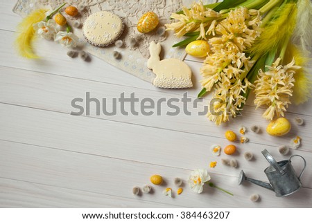 Easter white wooden background with yellow flowers hyacinth, narcissus, eggs and cakes, space for text, greeting