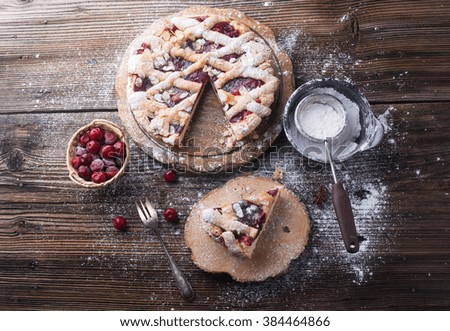 Delicious cake with cherries, icing sugar and a cup of coffee on a wooden background