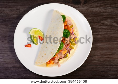 Tacos on a white plate on a dark background Board is served with lime