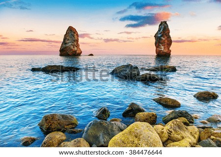 Sunset on the sea above big rocks. Landscape with coast and dramatic sky