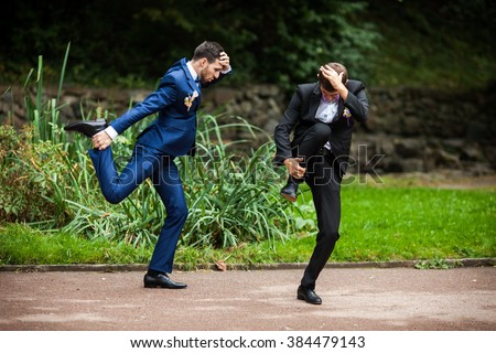 Groom and bestman dancing and goofing around after wedding ceremony in the park