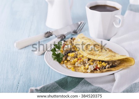 Omelet for breakfast with rice, mushrooms and corn on a blue wooden background. Selective focus.