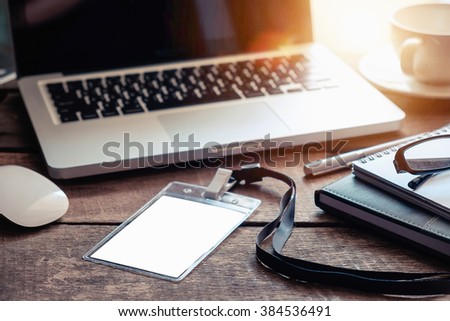 Office workplace with Employee Card laptop pen coffee cup and mouse on wood table in morning light.dark effect