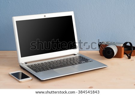 Office Desk with Computer Notebook, Cell Phone and camera. Business concept background.