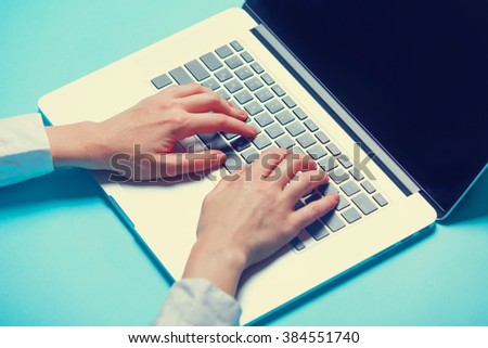 Woman typing on the notebook at blue background