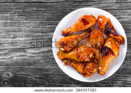 Grilled chicken sticky drumsticks marinated with honey and ginger on a white dish, top view Royalty-Free Stock Photo #384597385