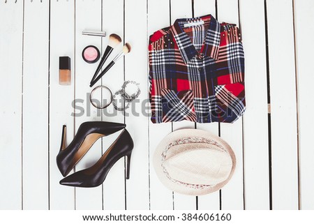 stylish collage of clothing on a wooden background with a shirt in a cage ornaments cosmetics and fashion shoes