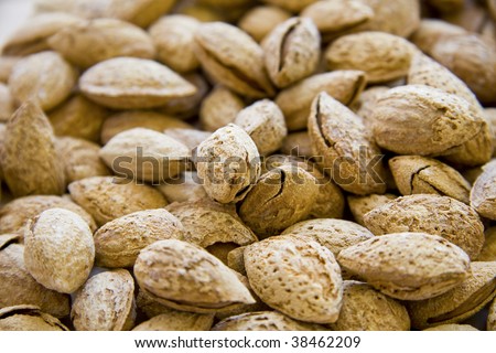 Closeup of a heap of almonds toasted in shells. Shallow depth of field.