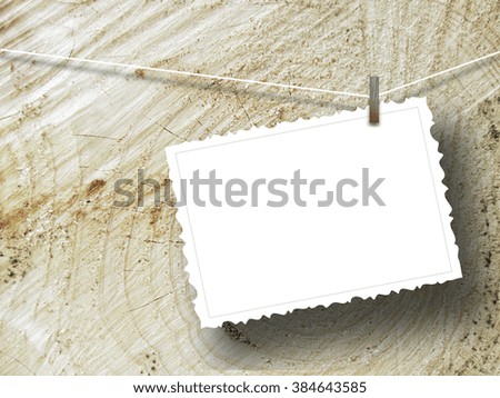 Close-up of one hanged postcard with peg on brown wooden trunk background