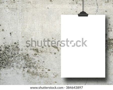 Close-up of one hanged paper sheet frame with clip on grey stained concrete wall background