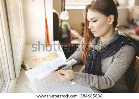 Woman leaf through a journal at the window