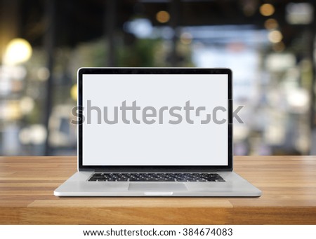 Laptop on table against bokeh lights background,blank screen