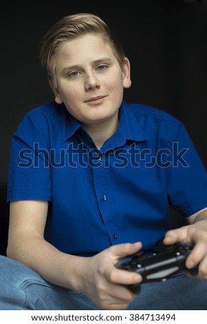 Single calm boy in blue shirt holding controller in lap after he is finished playing video games