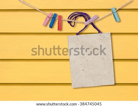 Blank paper bag hang with clothespin on yellow wooden wall.