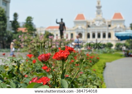 Red Roses in Focus with Blurred Monument and a Yellow People's City Committee Building in the Background in Vietnam