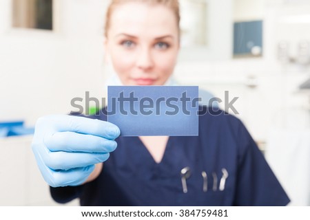 Closeup of business card hold by female dentist with copyspace as blank empty sign concept