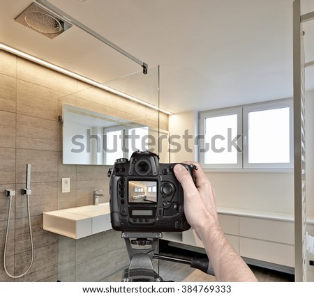 Hands holding a professional camera on tripod taking picture in Luxury Bathroom Estate Home Shower
