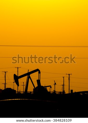 Silhouette of crude oil pump in oil field at sunset.