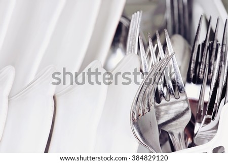 Abstract of clean forks and dishes inside of a dish washing machine. Extreme shallow depth of field with selective focus on fork.