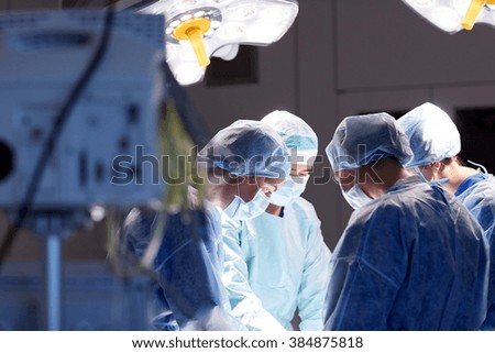 surgery, medicine and people concept - group of surgeons at operation in operating room at hospital Royalty-Free Stock Photo #384875818